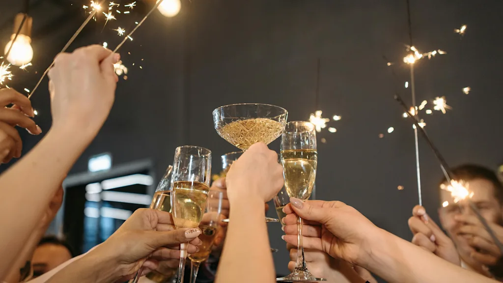Hender holder champagneglass og stjerneskudd, feirer en spesiell anledning.