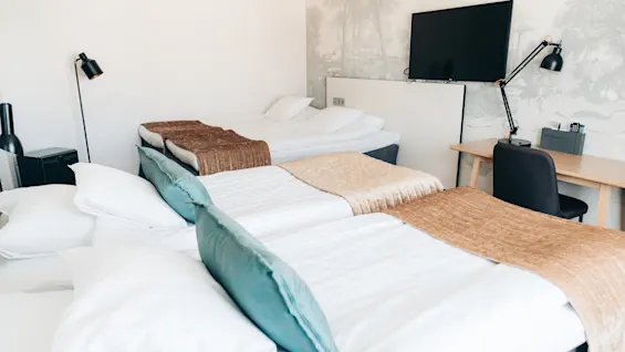 Bright hotel room with multiple made beds ready for guests