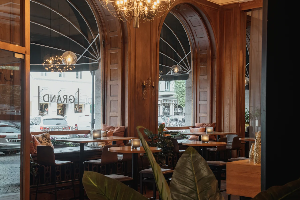 Mysig hotellinteriör med träpaneler, välvda fönster och inbjudande sittplatser. GRAND-skylt synlig utanför. Home Hotel Grand, Helsingborg.