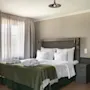 Kutsuva hotellihuone, jossa on mukava sänky, raikkaat valkoiset liinavaatteet, vihreä peitto ja kaksi pehmeää kylpytakkia.