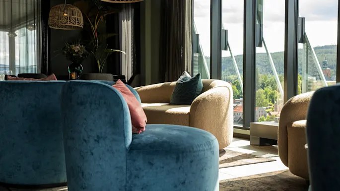 Cozy lounge with modern seating and large windows overlooking a scenic green landscape.