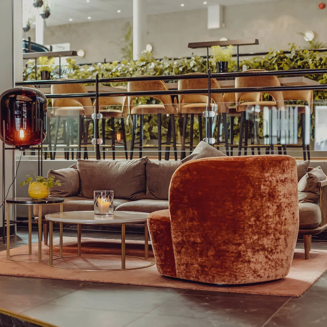 A cozy lounge area with plush velvet chairs, a sofa, a fireplace, and unique lighting fixtures, exudes warmth and modern elegance.
