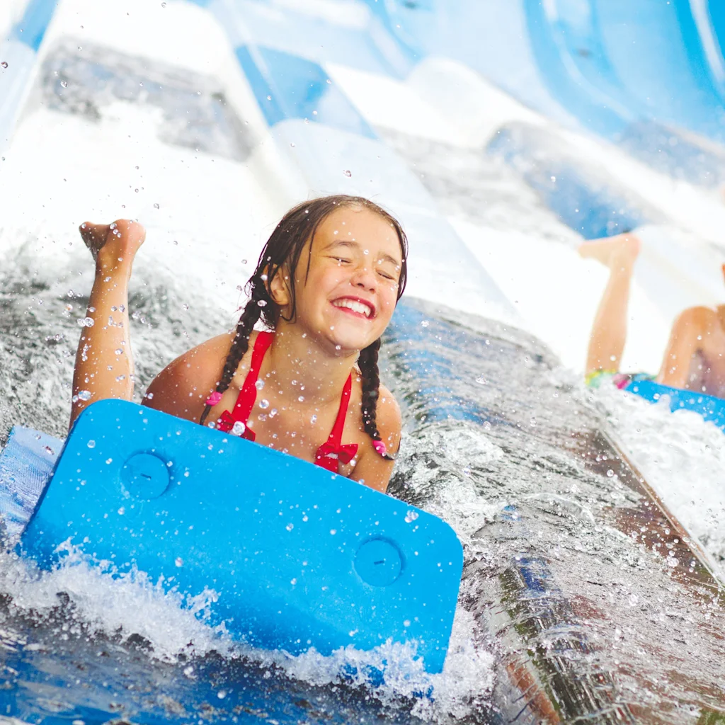 Two happy children sliding down a water slide at Skara Sommarland, enjoying the splash and fun.