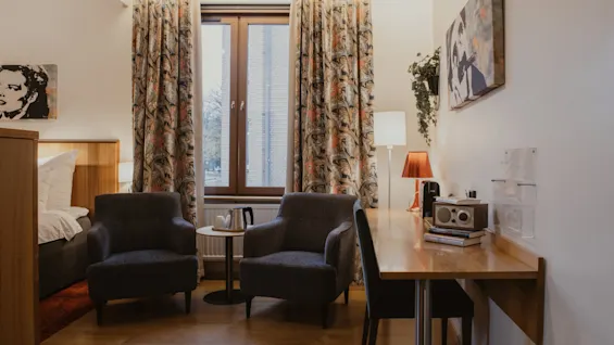 A welcoming hotel room at Home Hotel Kung Oscar, featuring a comfortable bed, a cozy seating area, and a functional desk.