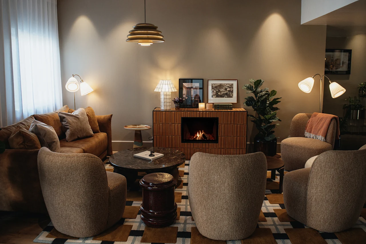 En varm och inbjudande lounge med en tänd öppen spis, bekväma sittplatser och mjuk belysning, perfekt för avkoppling.