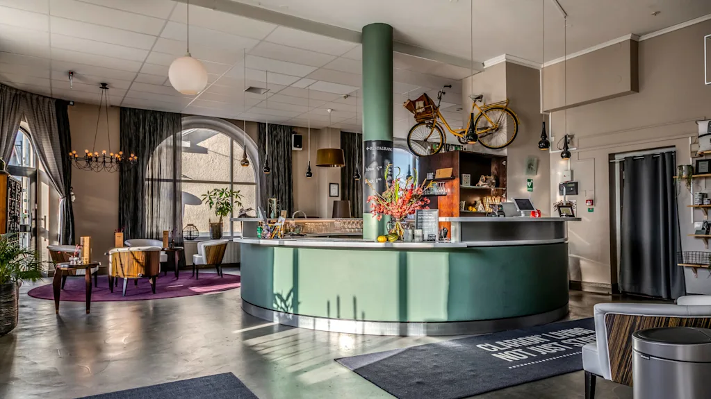 Ett modernt hotellfoajé med stilfulla möbler, en cykel upphängd ovanför receptionsdisken, i ett rymligt, välbelyst rum.