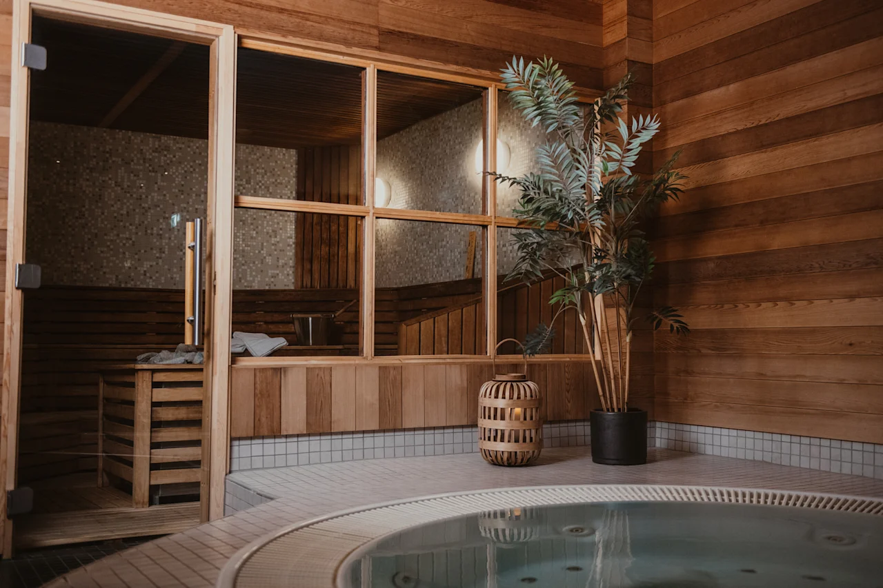 Ett mysigt spaområde med en träbastu med glasdörrar och en bubblande bubbelpool, omgiven av varma träväggar.
