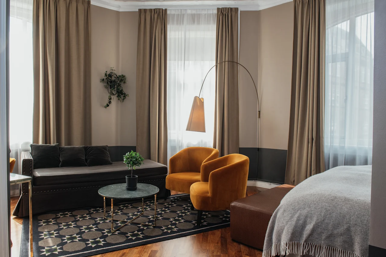 Et innbydende hotellrom med et komfortabelt salongområde, komplett med en sofa, to lenestoler og myk belysning.