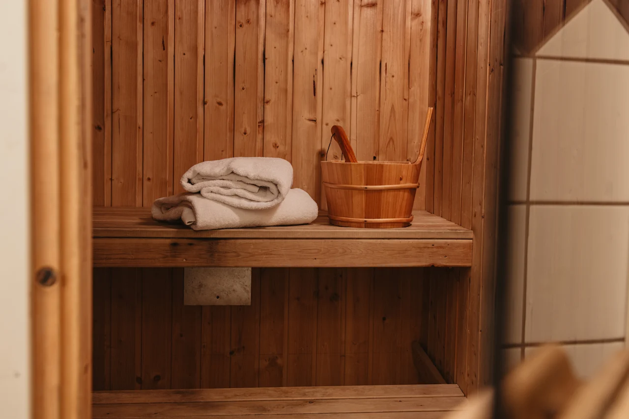 En hyggelig træsauna med håndklæder og en vandspand, klar til afslapning.