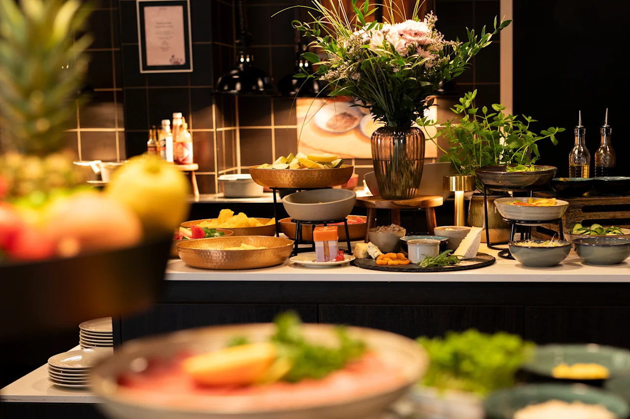 En livlig buffé med frisk frukt, oster og ulike retter, pyntet med et vakkert blomsterarrangement.