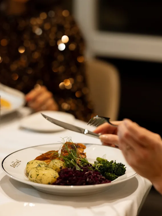 Guests in festive outfits enjoying a lovely dinner with delicious food at a restaurant.