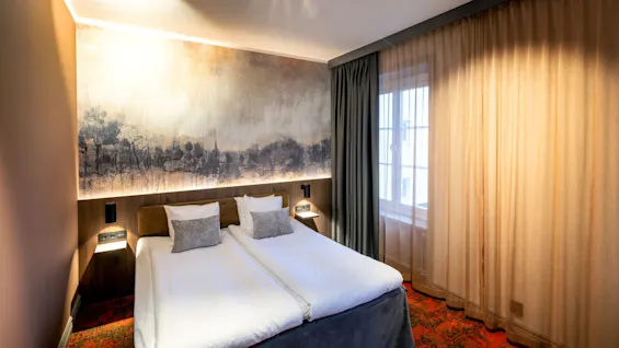 A well-lit bedroom with a large bed, abstract wall art, and golden curtains, capturing a comfortable, modern interior.