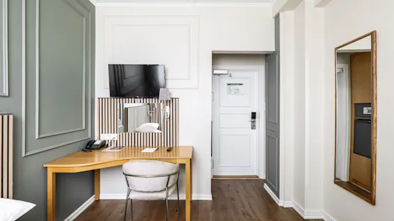 Moderni hotellihuone Comfort Hotel Linköping Cityssä, jossa on työpöytä, tuoli, TV ja ovi käytävälle.