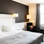 Et indbydende hotelværelse med en plys seng, en komfortabel lænestol og blød belysning, der skaber en rolig atmosfære.