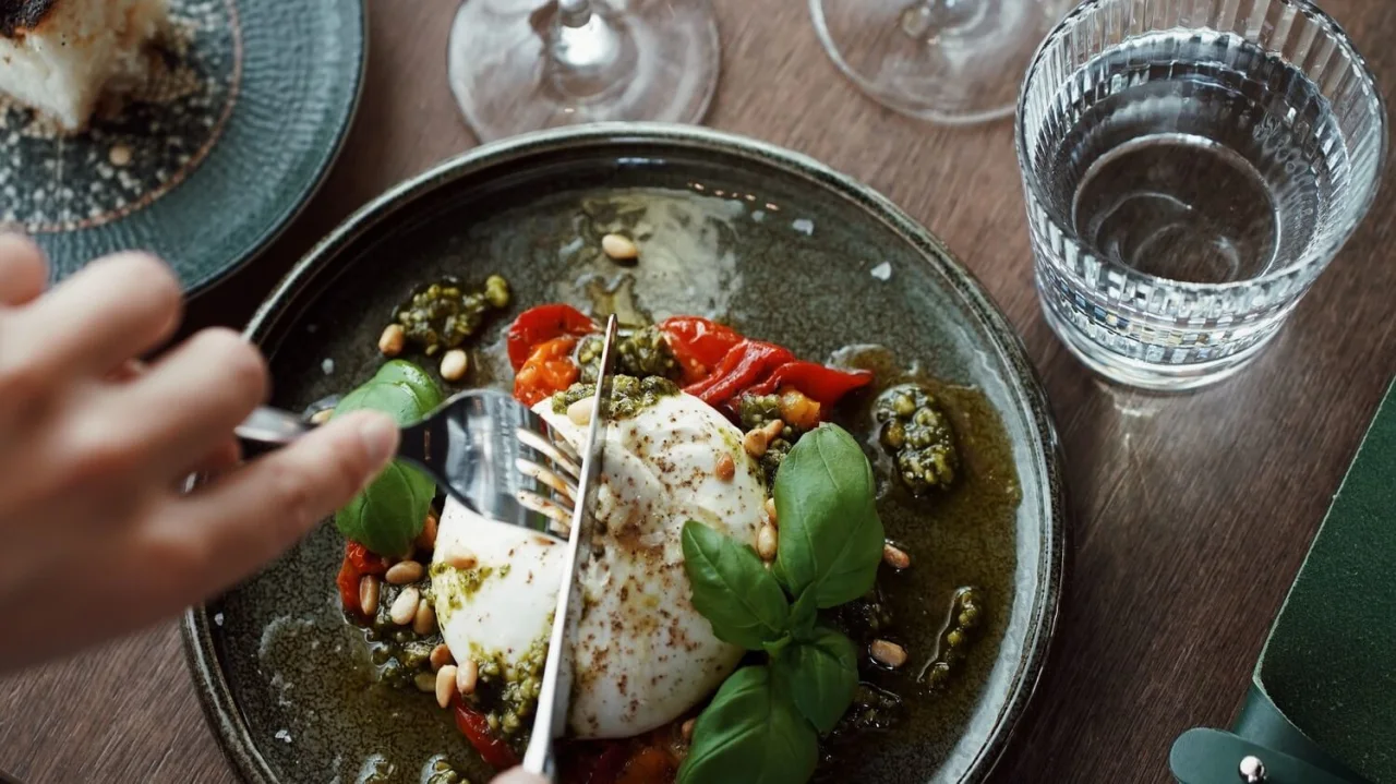 Cutting up a burrata on a plats at restaurant NÒR.