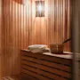 Home Hotel Kung Oscar sauna interior with warm wooden benches, towels, and a bucket, ready for relaxation.