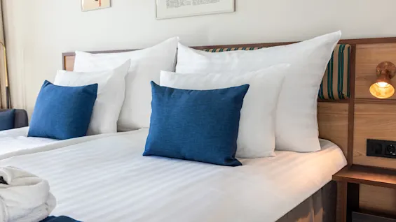 A comfortable bed with white linens and blue pillows at Quality Hotel The Book in Gothenburg, ready for a relaxing stay.