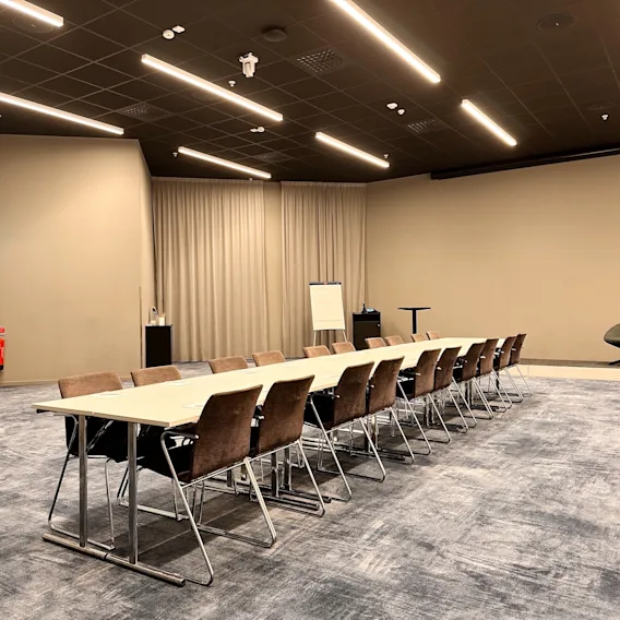 Modernt konferensrum på Quality Hotel Arlanda XPO med långt mötesbord, stolar, whiteboard och presentationsyta.