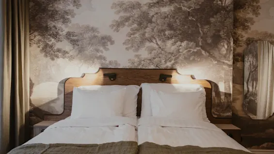 Home Hotel Baltzar - Superior Room. A comfortable bed with a wooden headboard and serene, nature-themed wallpaper.