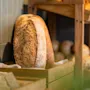 Freshly baked loaves of bread displayed in wooden crates on a shelf, ready for serving.