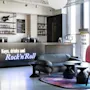 A modern reception desk displays the text "Keys, drinks and Rock'n'Roll" with a guitar and bottles above. Comfortable seating and colorful decor enhance the welcoming lounge atmosphere.