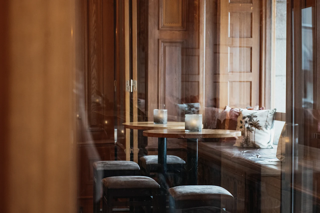 En varm och inbjudande lounge med träpaneler, små bord och mjukt levande ljus på Home Hotel Grand, Helsingborg.