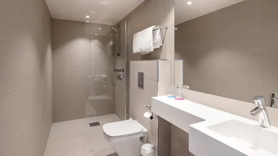 Et moderne bad med en glassinnrammet dusj, vegghengt toalett og strømlinjeformet servant med stor speil. Beige fliser dekker vegger og gulv, og gir et minimalistisk utseende.