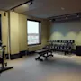 Et velutstyrt hotellgym på Stopover Hotel Falkenberg med en trimsykkel, vektbenk og manualer, klart for en treningsøkt.