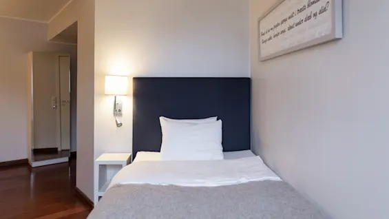 Enkel säng med lampa och text: Palli prapten ringe mitt i tracts blomstertid Hope the heroes are devet under slab og slid