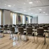 A spacious, modern conference room with rows of tables and chairs, ready for a meeting or presentation.
