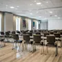 A spacious, modern conference room with rows of tables and chairs, ready for a meeting or presentation.