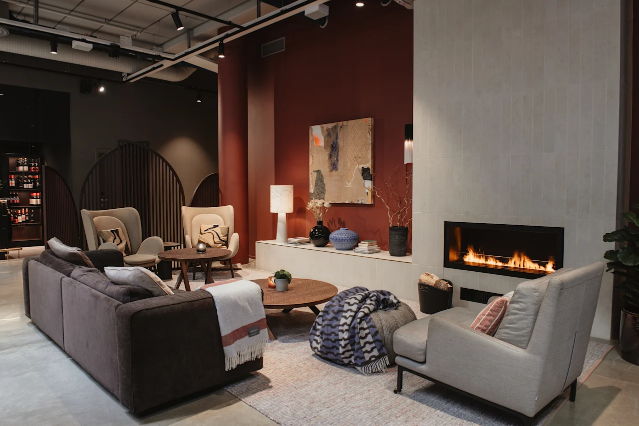 Inviting lounge at Home Hotel Tapetfabriken with a lit fireplace, plush sofas, and armchairs, perfect for relaxation.