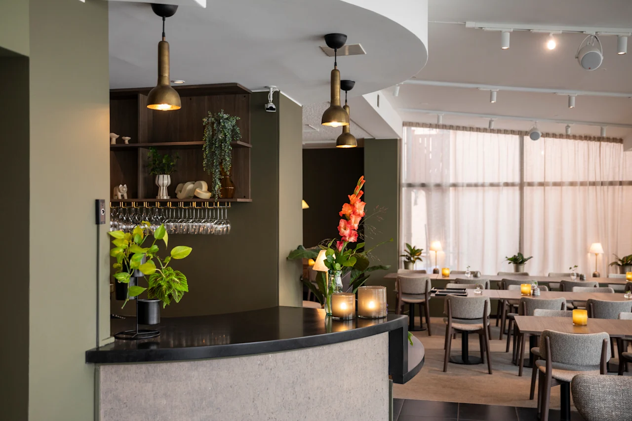 Kutsuva hotellilounge, jossa on tyylikäs baari ja ruokailutila lämpimällä valaistuksella ja mukavilla istuimilla.