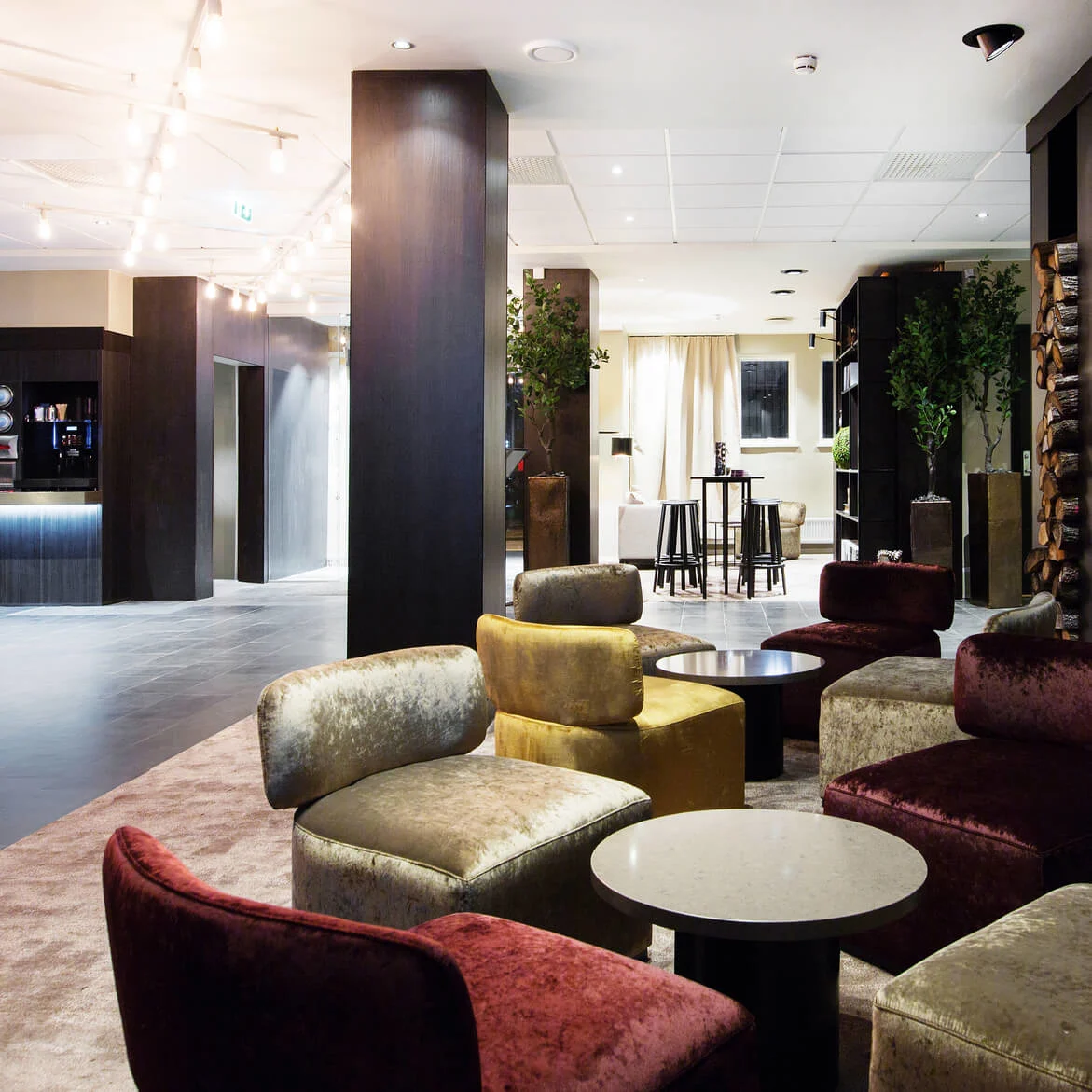 Luksuriøse sitteområder med komfortable stoler omgir bord ved siden av en elegant, moderne peis. Den romslige salongen har stemningsfull belysning og en snackbar i bakgrunnen.