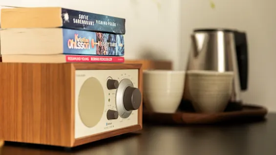 En mysig hotellrumsscen med träradio, böcker, vattenkokare och koppar, för en avkopplande vistelse på Home Hotel Tapto.