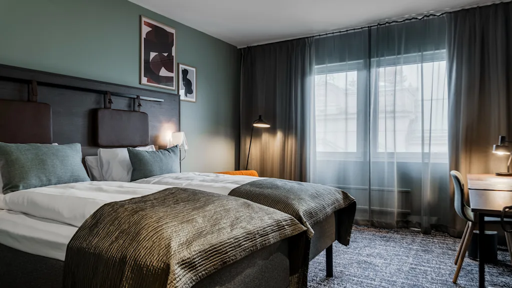 Ett bekvämt hotellrum på Quality Hotel Luleå med två sängar, ett skrivbord och ett fönster.