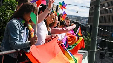En grupp människor som står på en balkong och viftar med Pride-flaggor