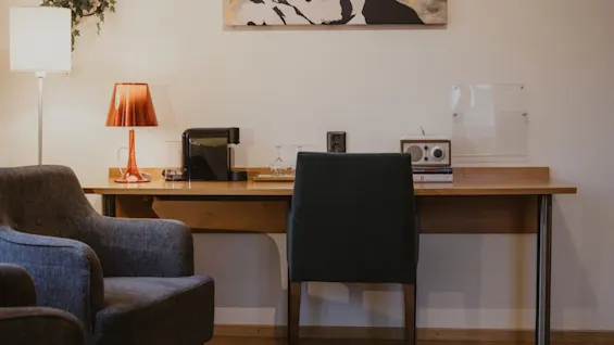 A cozy desk area with a coffee machine, lamp, and radio, perfect for work or relaxation at Home Hotel Kung Oscar.