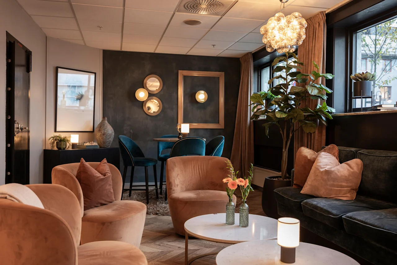 A stylish and inviting hotel lounge at Home Hotel Grand Bodø, featuring comfortable seating, warm lighting, and modern decor.