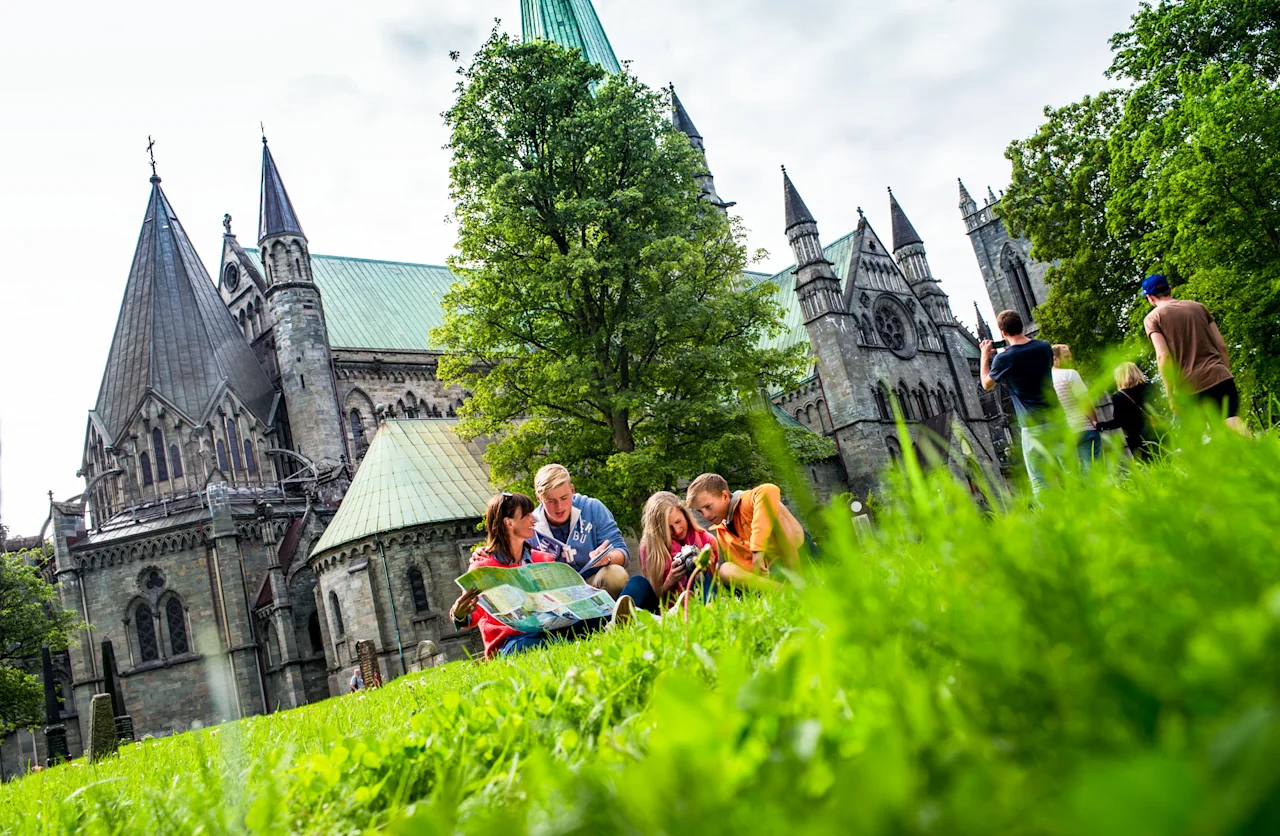Folk udforsker historiske katedralområder, nogle kigger på et kort, andre nyder landskabet.