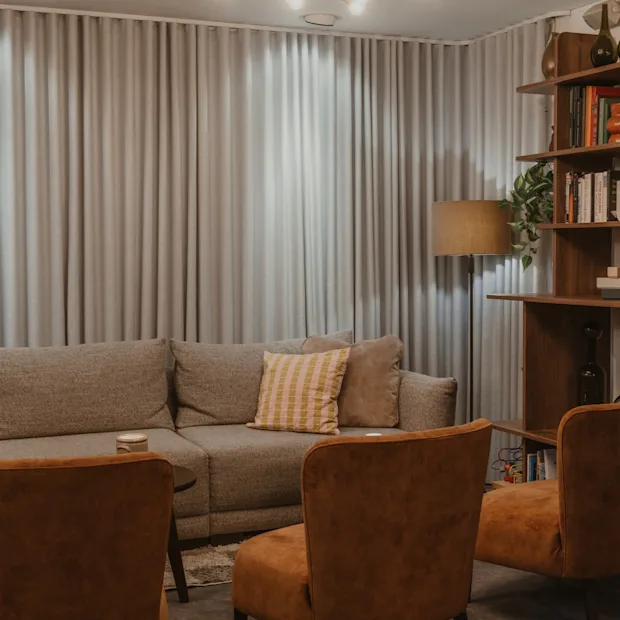 Home Hotel Victoria. Viihtyisä oleskelutila, jossa sohva, nojatuolit, kirjahylly ja lämmin valaistus, täydellinen rentoutumiseen.