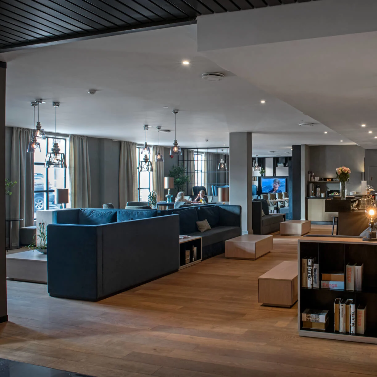 Ett modernt hotelllobby med bekväm sittplats, dämpad belysning och en synlig receptionsdisken. Människor sitter och samtalar.