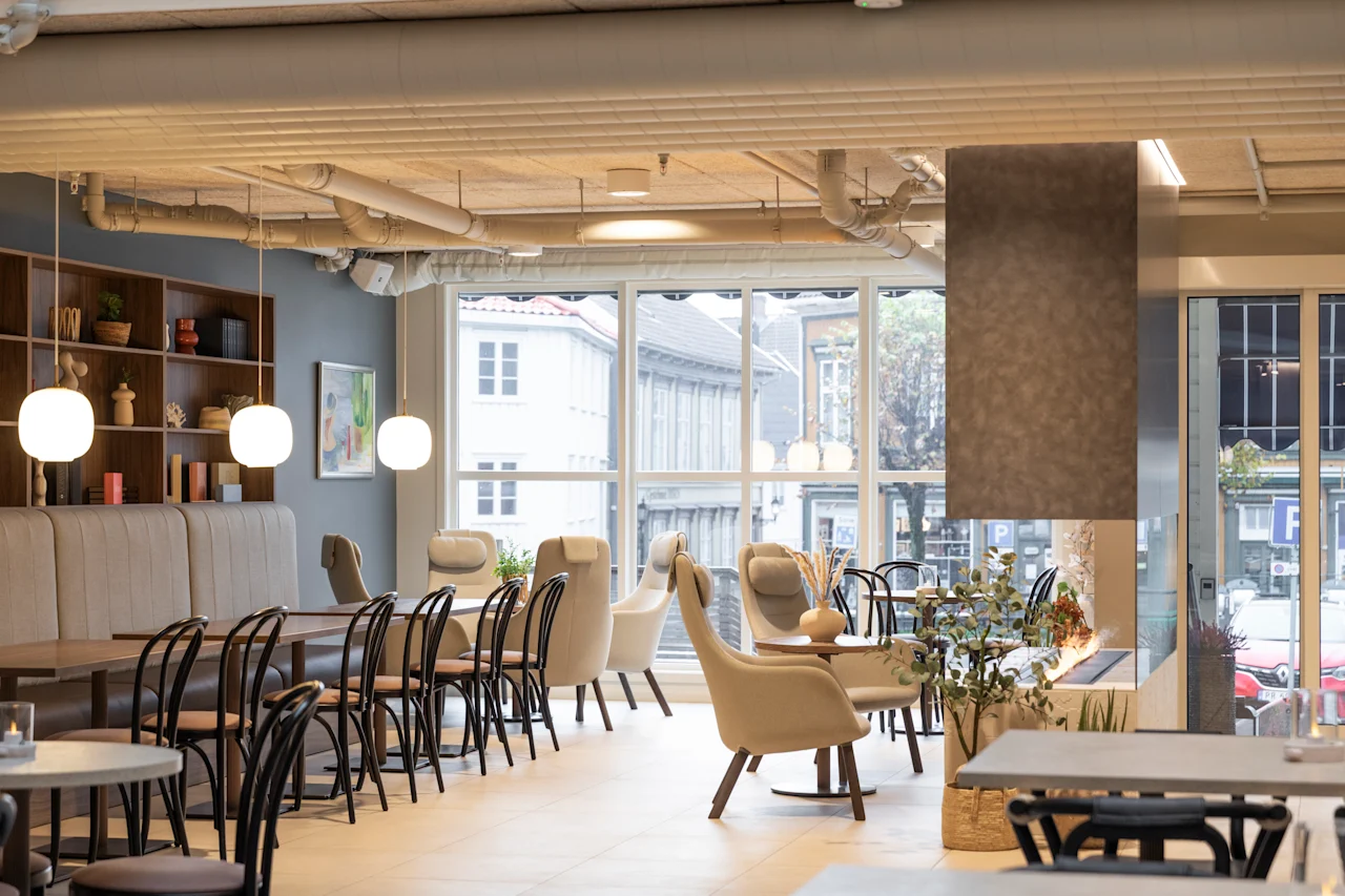 A bright and inviting lounge area with comfortable seating, large windows, and a modern fireplace, perfect for relaxation.