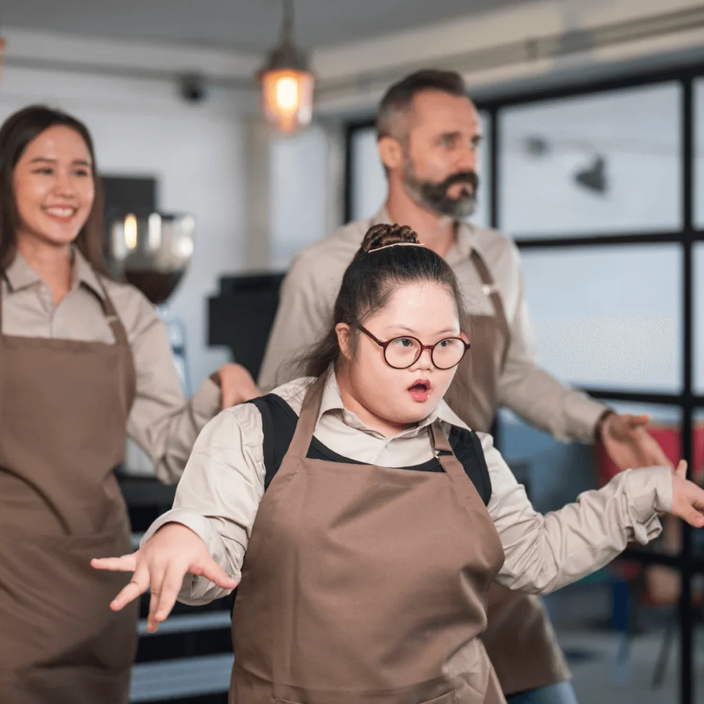 Tre baristaer i forkler danser entusiastisk innendørs.