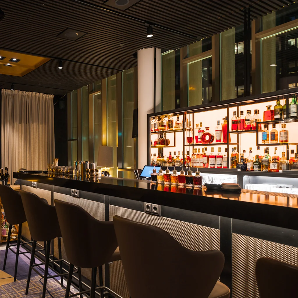 En sofistikert hotellbar med glødende bar, komfortable sitteplasser og opplyste hyller, som skaper en varm og innbydende atmosfære.