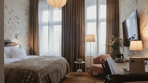 Home Hotel Baltzar - Deluxe Double. A cozy hotel room with a comfortable bed, a desk area, and large windows with curtains.