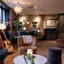 A warm and inviting lounge area at Home Hotel Grand Bodø, featuring comfortable seating, soft lighting, and a guitar, suggesting a relaxed atmosphere.