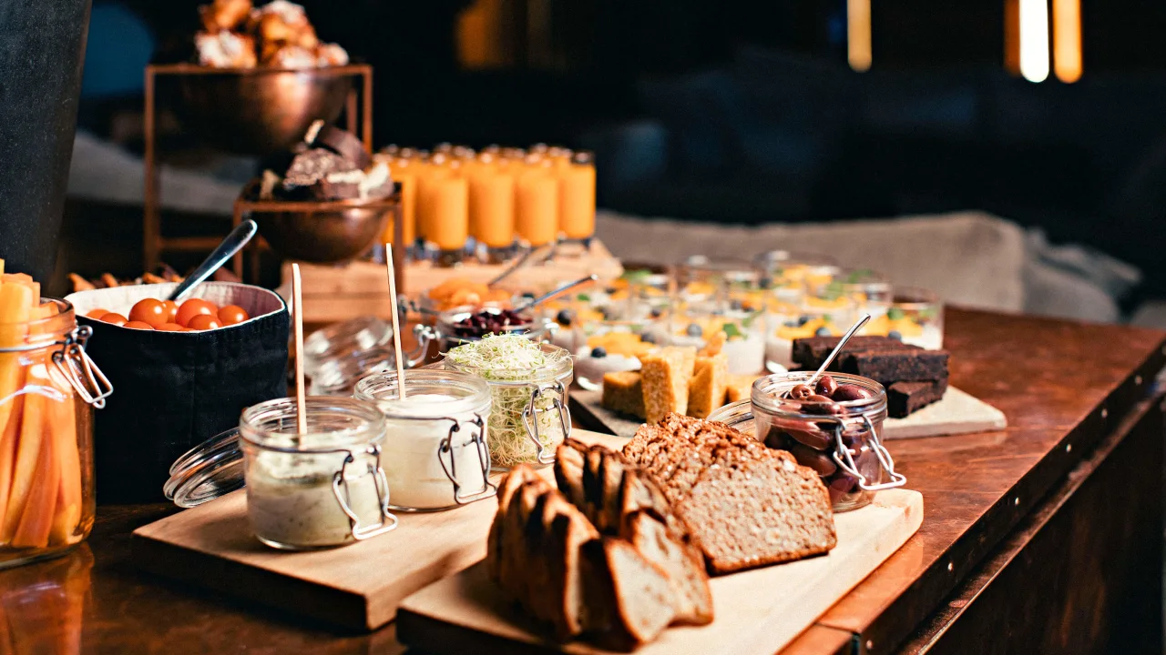 En buffet med ulike frokostvarer spredt utover et trebord med stemningsfull belysning i bakgrunnen på Copperhill Mountain Lodge hotell.