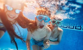 Children wearing goggles playing under water in the pool.