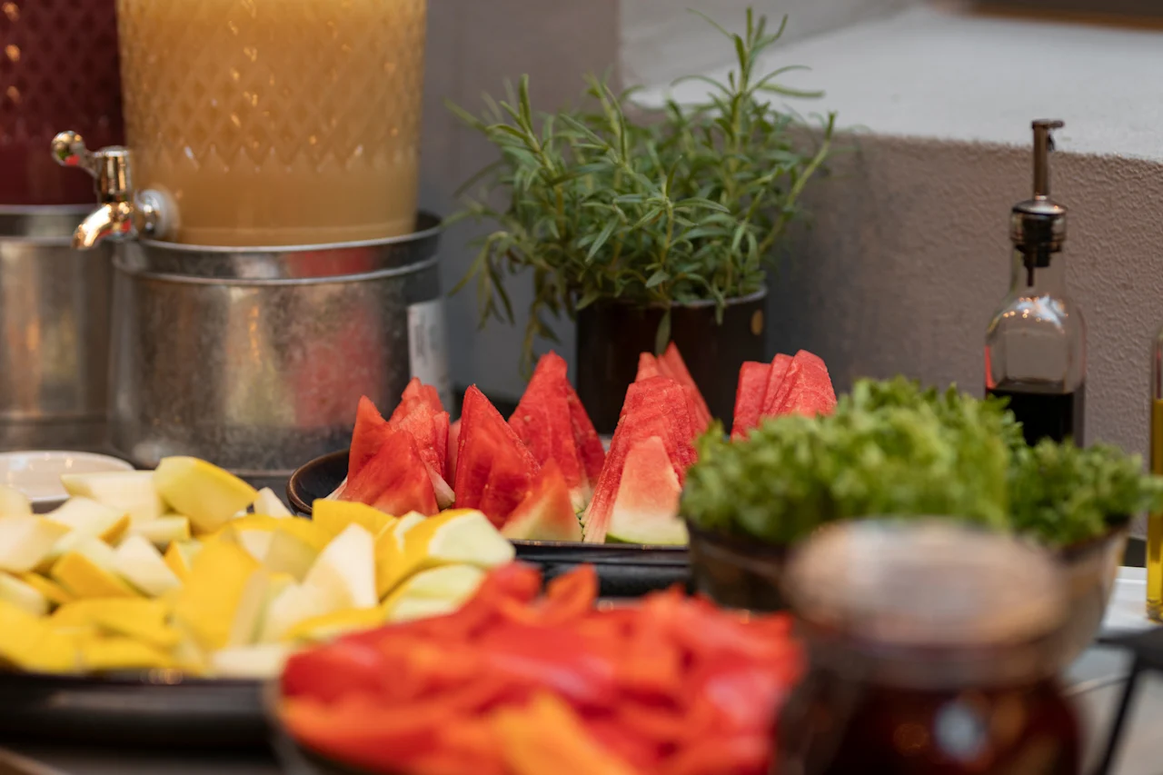 Fresh and colorful buffet at Home Hotel Grand Bodø with sliced watermelon, fruits, salad, and a refreshing drink.